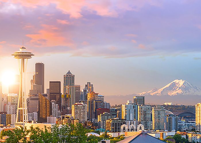 Seattle sightseeing offers a stunning view of the skyline with the iconic Space Needle, city buildings, and Mount Rainier under a colorful sky. Explore this breathtaking scene on custom Seattle tours designed just for you.